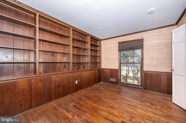 empty room featuring wooden walls, a wainscoted wall, and wood-type flooring