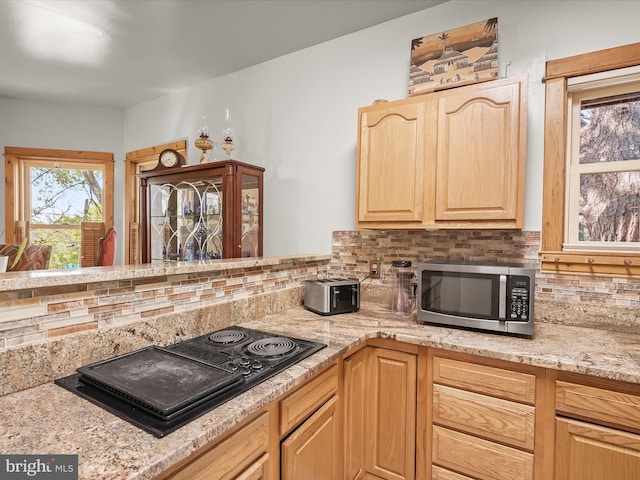 3137 18th St NE, Washington, DC 20018 - kitchen with black electric cooktop, light stone counters, light brown cabinets, stainless steel microwave, and tasteful backsplash
