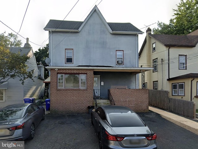 view of front of home with stucco siding, fence, and brick siding