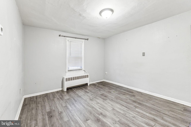 unfurnished room with baseboards, radiator heating unit, and wood finished floors