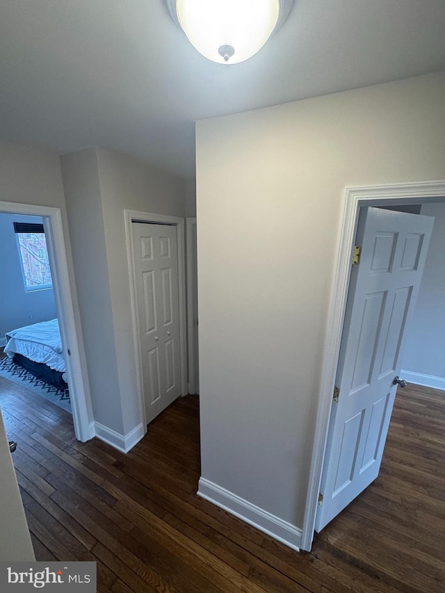 corridor featuring dark wood-style floors and baseboards