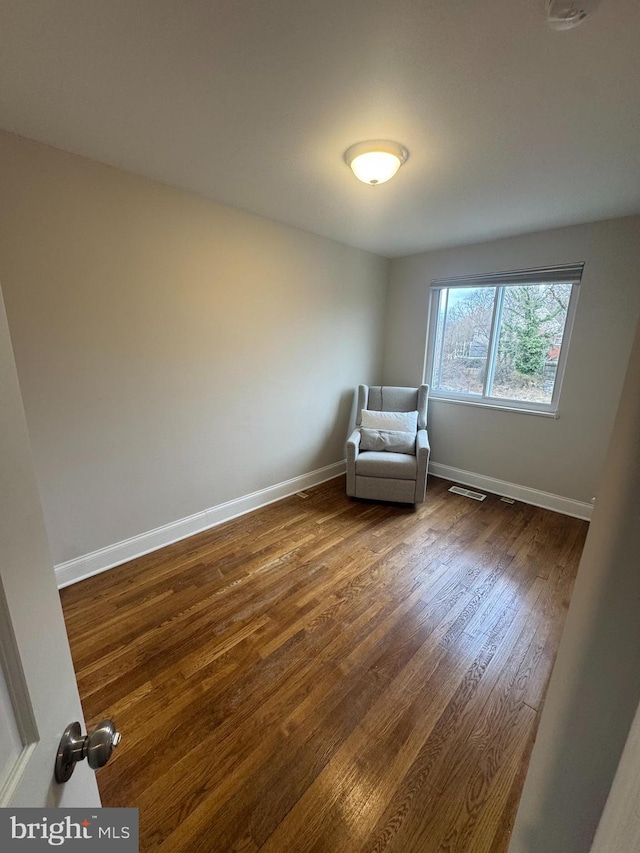 unfurnished room with dark wood-type flooring, visible vents, and baseboards