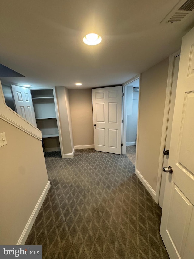 finished basement with dark carpet, visible vents, and baseboards