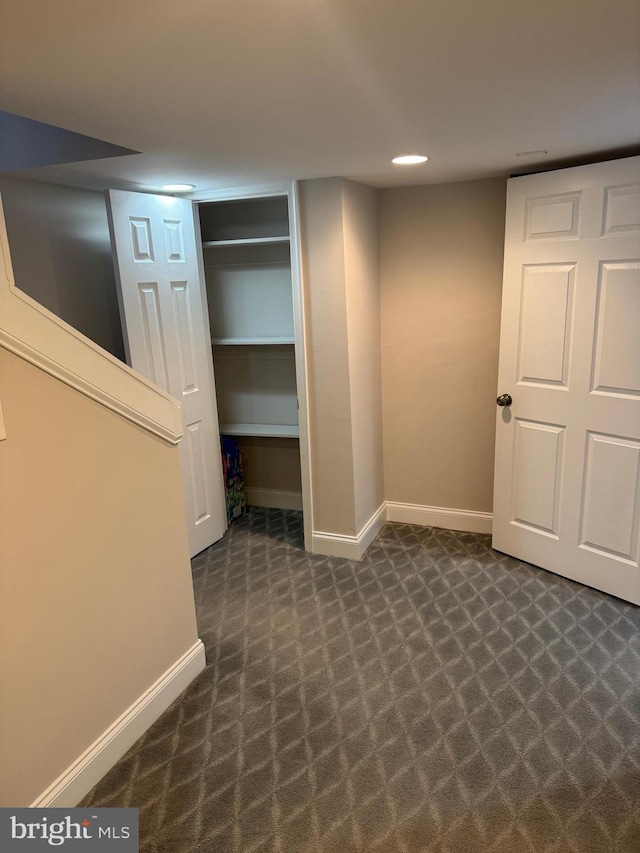 finished below grade area featuring dark colored carpet and baseboards