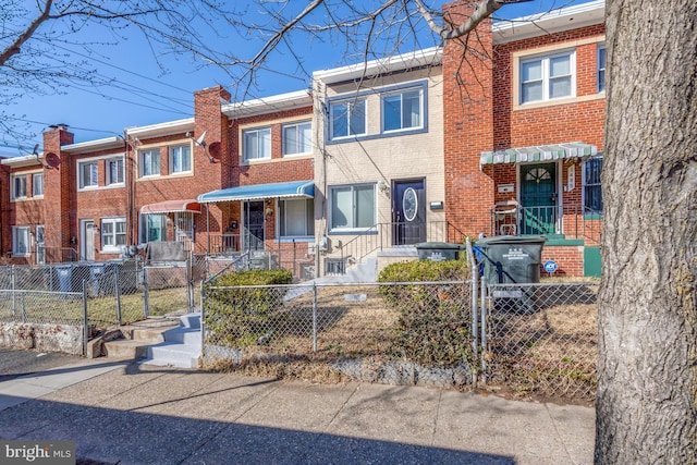 multi unit property with a fenced front yard, a gate, and brick siding