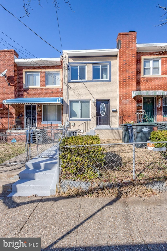 multi unit property with a fenced front yard, a gate, and brick siding