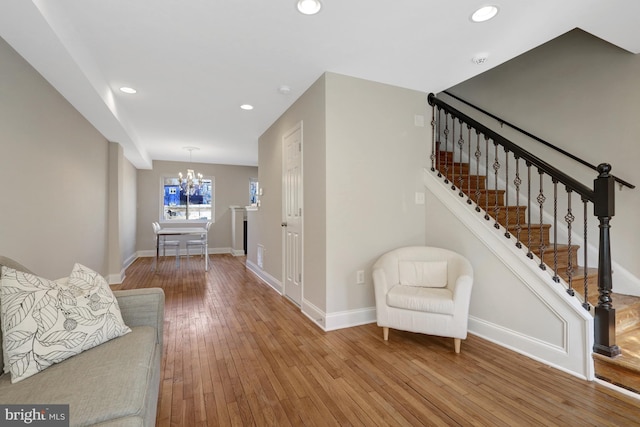 living room featuring baseboards, stairway, hardwood / wood-style floors, a notable chandelier, and recessed lighting