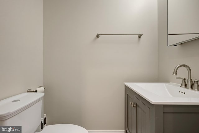 half bath featuring toilet, baseboards, and vanity