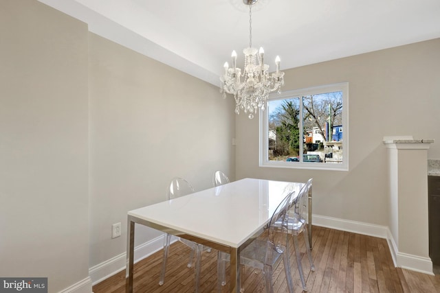 dining space with a chandelier, baseboards, and hardwood / wood-style floors