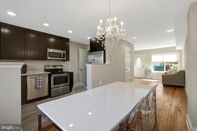 kitchen with a breakfast bar area, wood finished floors, stainless steel appliances, light countertops, and recessed lighting