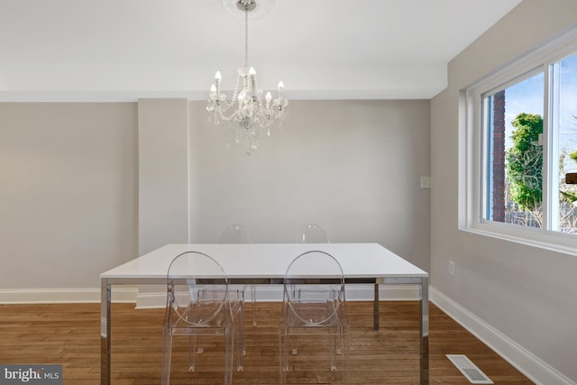 dining room featuring a notable chandelier, wood finished floors, visible vents, and baseboards