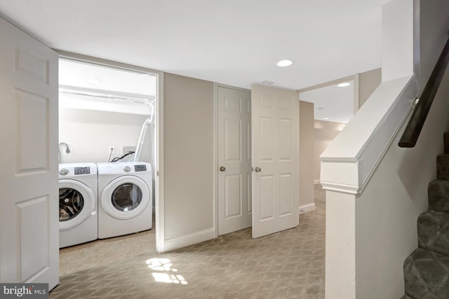 laundry area with washer and dryer, laundry area, light colored carpet, and baseboards