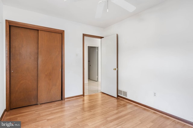 unfurnished bedroom featuring ceiling fan, light wood-type flooring, and a closet