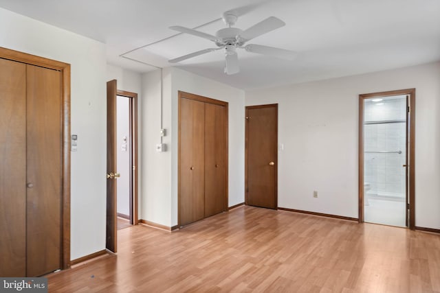 unfurnished bedroom featuring multiple closets, ensuite bathroom, ceiling fan, and light hardwood / wood-style flooring