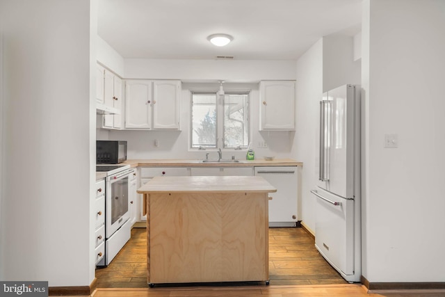 kitchen with sink, light hardwood / wood-style flooring, a kitchen island, white appliances, and white cabinets