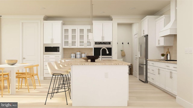 kitchen with premium range hood, a center island with sink, and white cabinets