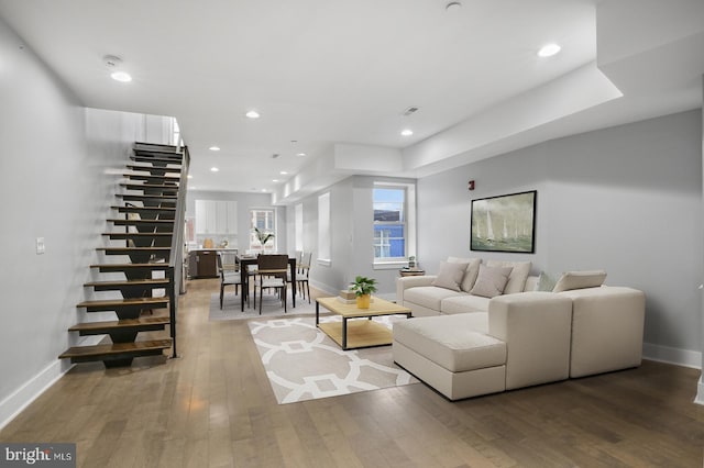 living area featuring baseboards, recessed lighting, stairway, and wood finished floors