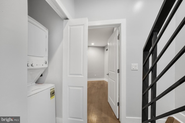 laundry room with baseboards, stacked washer and dryer, wood finished floors, and laundry area