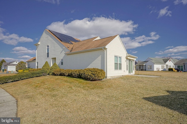 view of side of property featuring a yard and solar panels