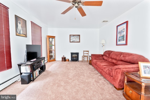 carpeted living room with ceiling fan, baseboard heating, and a wood stove