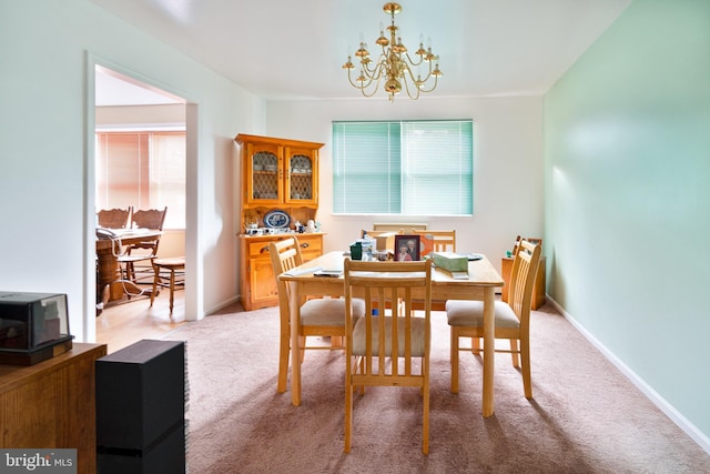 dining space featuring light colored carpet and a chandelier