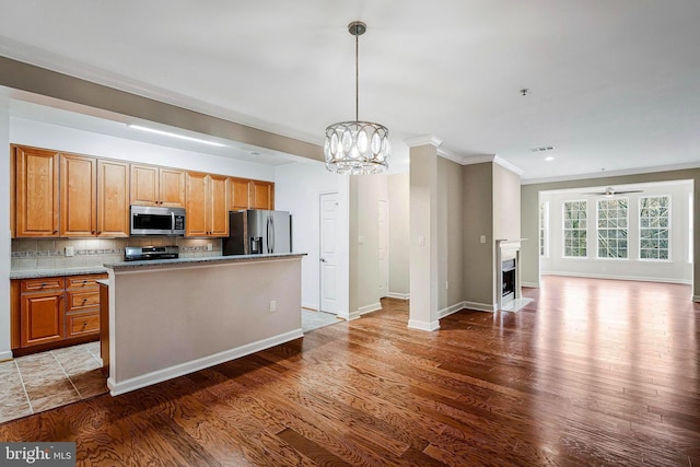 kitchen with appliances with stainless steel finishes, a kitchen island, tasteful backsplash, and dark hardwood / wood-style floors