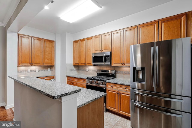 kitchen with light tile patterned floors, a center island, stainless steel appliances, light stone countertops, and decorative backsplash