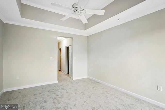 carpeted empty room with a tray ceiling, ornamental molding, and ceiling fan