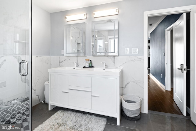 bathroom with tile walls, an enclosed shower, vanity, and tile patterned floors