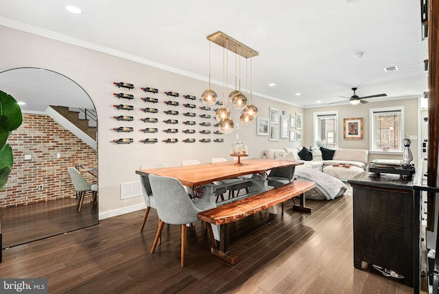 dining space with crown molding, brick wall, and dark wood-type flooring