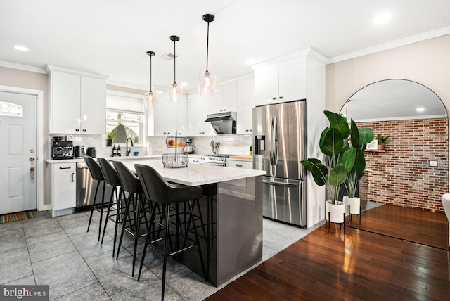 kitchen featuring pendant lighting, stainless steel appliances, white cabinets, and a kitchen island