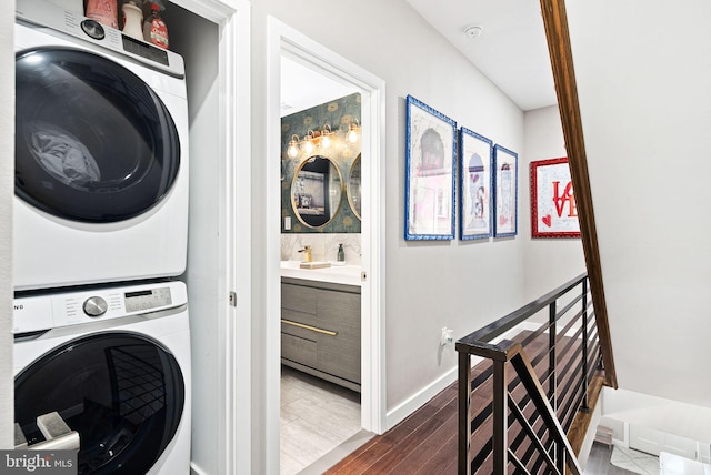 clothes washing area featuring hardwood / wood-style floors and stacked washer and clothes dryer