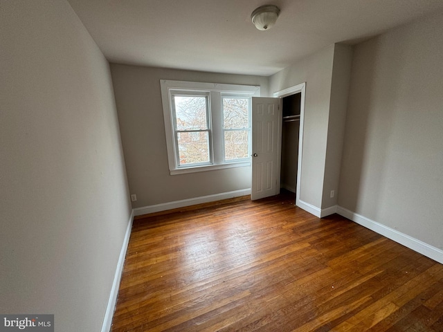 unfurnished bedroom with wood-type flooring and a closet