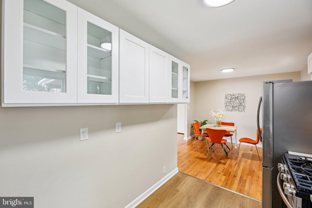 kitchen with appliances with stainless steel finishes, light hardwood / wood-style floors, and white cabinets