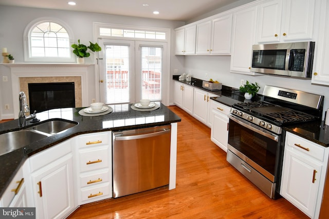 kitchen featuring white cabinets, appliances with stainless steel finishes, light wood-style floors, and a sink