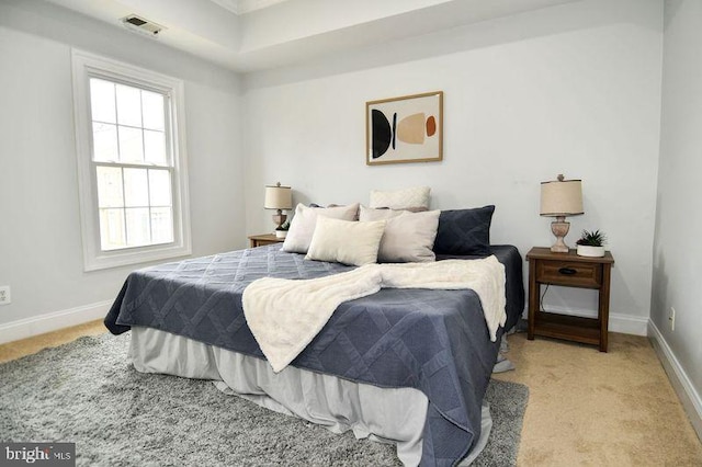 bedroom featuring light carpet, visible vents, and baseboards