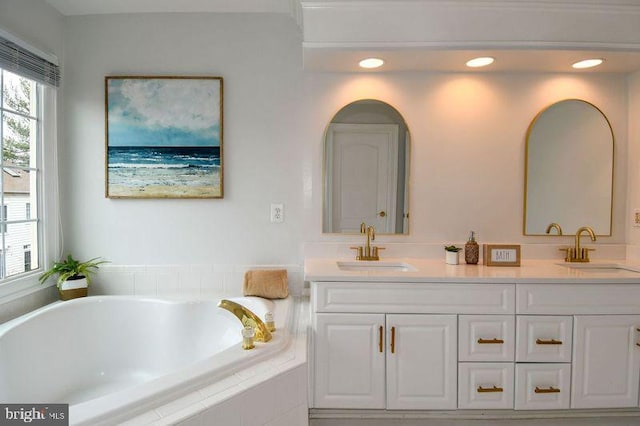 bathroom featuring a sink, recessed lighting, double vanity, and tiled bath