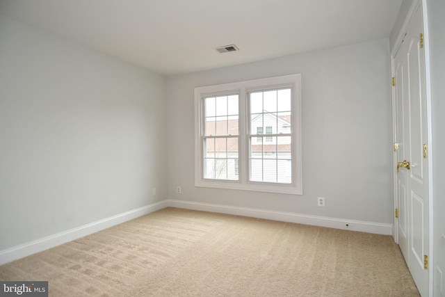 carpeted spare room featuring visible vents and baseboards