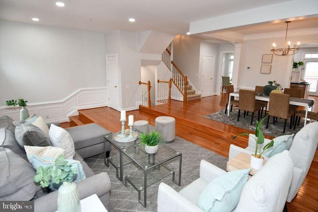 living room featuring wood finished floors, recessed lighting, stairway, an inviting chandelier, and a decorative wall