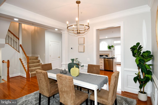 dining area with stairs, crown molding, wood finished floors, and a chandelier