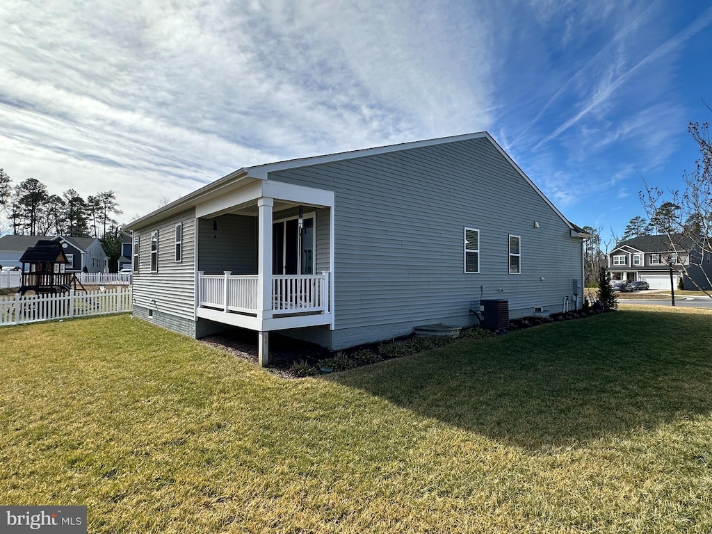 view of side of home with central AC unit and a yard