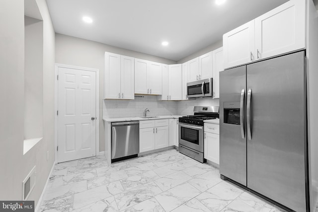 kitchen featuring tasteful backsplash, stainless steel appliances, sink, and white cabinets