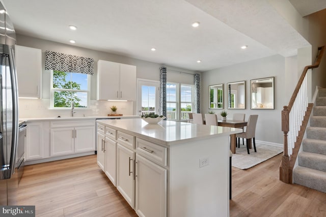 kitchen with sink, white cabinetry, tasteful backsplash, a center island, and light hardwood / wood-style flooring