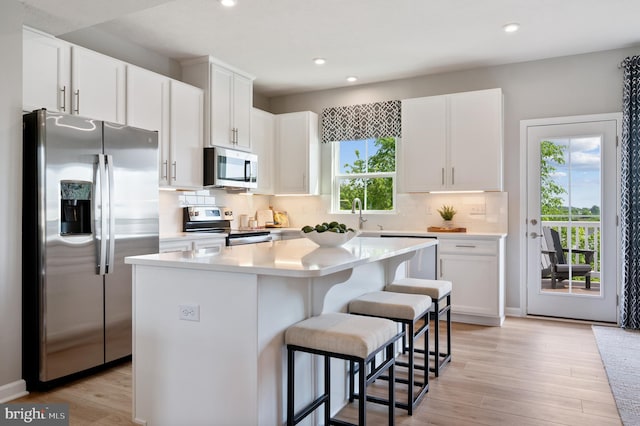 kitchen featuring a breakfast bar, white cabinetry, tasteful backsplash, appliances with stainless steel finishes, and a kitchen island