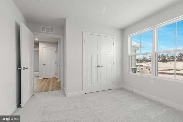 unfurnished bedroom with light colored carpet and a closet