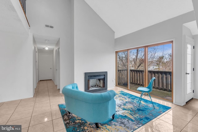 living room featuring high vaulted ceiling, baseboards, a fireplace, and visible vents