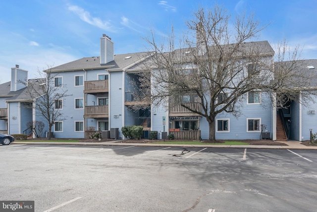 view of property with uncovered parking and cooling unit