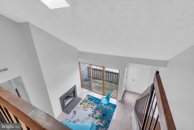 living room featuring light tile patterned floors, a textured ceiling, a skylight, and visible vents