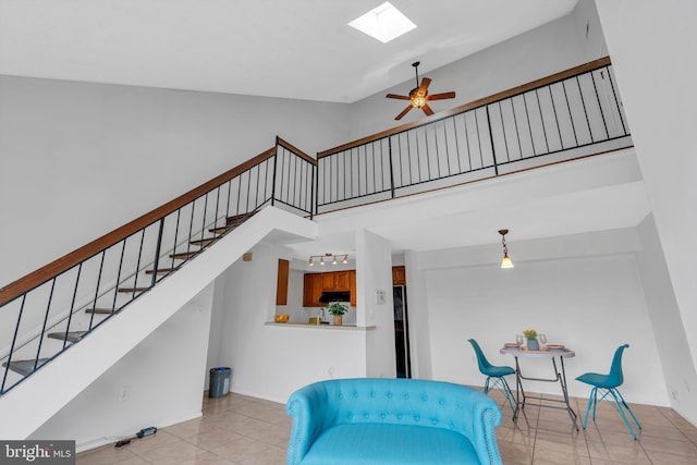 interior space featuring high vaulted ceiling, a skylight, tile patterned flooring, and a ceiling fan