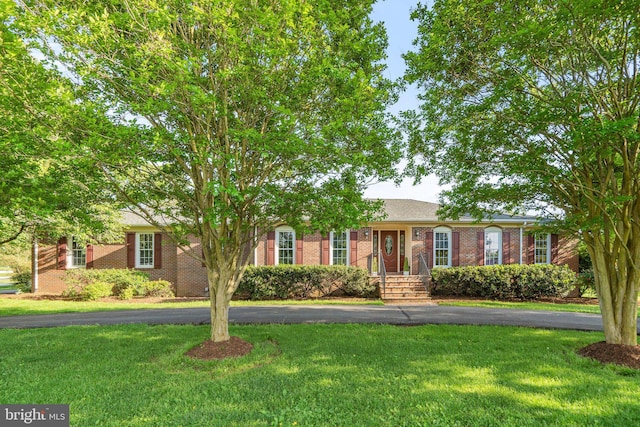 ranch-style home with aphalt driveway, a front lawn, and brick siding